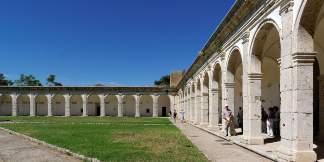 Grand cloître de la Chartreuse Saint-Jacques à Capri avec ses arches en pierre et sa pelouse centrale.