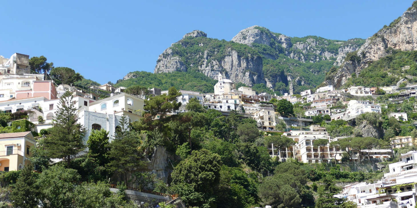 Chiesa Nuova à Positano avec maisons sur la colline et montagnes en arrière-plan.