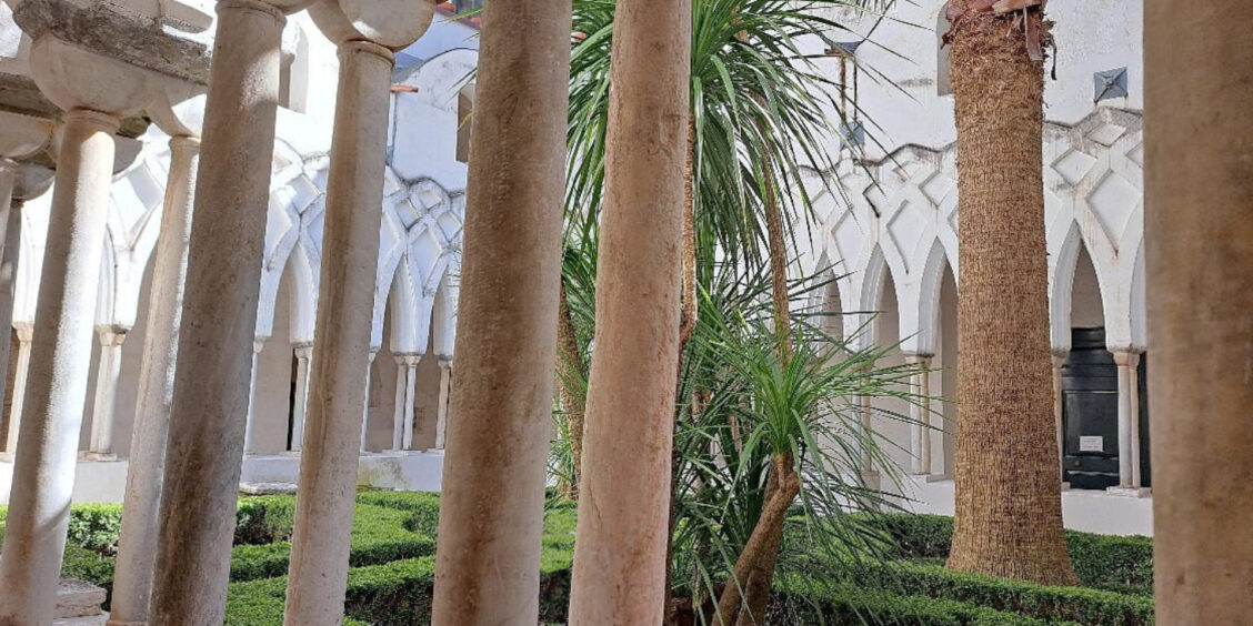 Les fines colonnes blanches et les arches entrelacées de style maure du Cloître du Paradis à Amalfi, entourant un jardin luxuriant.