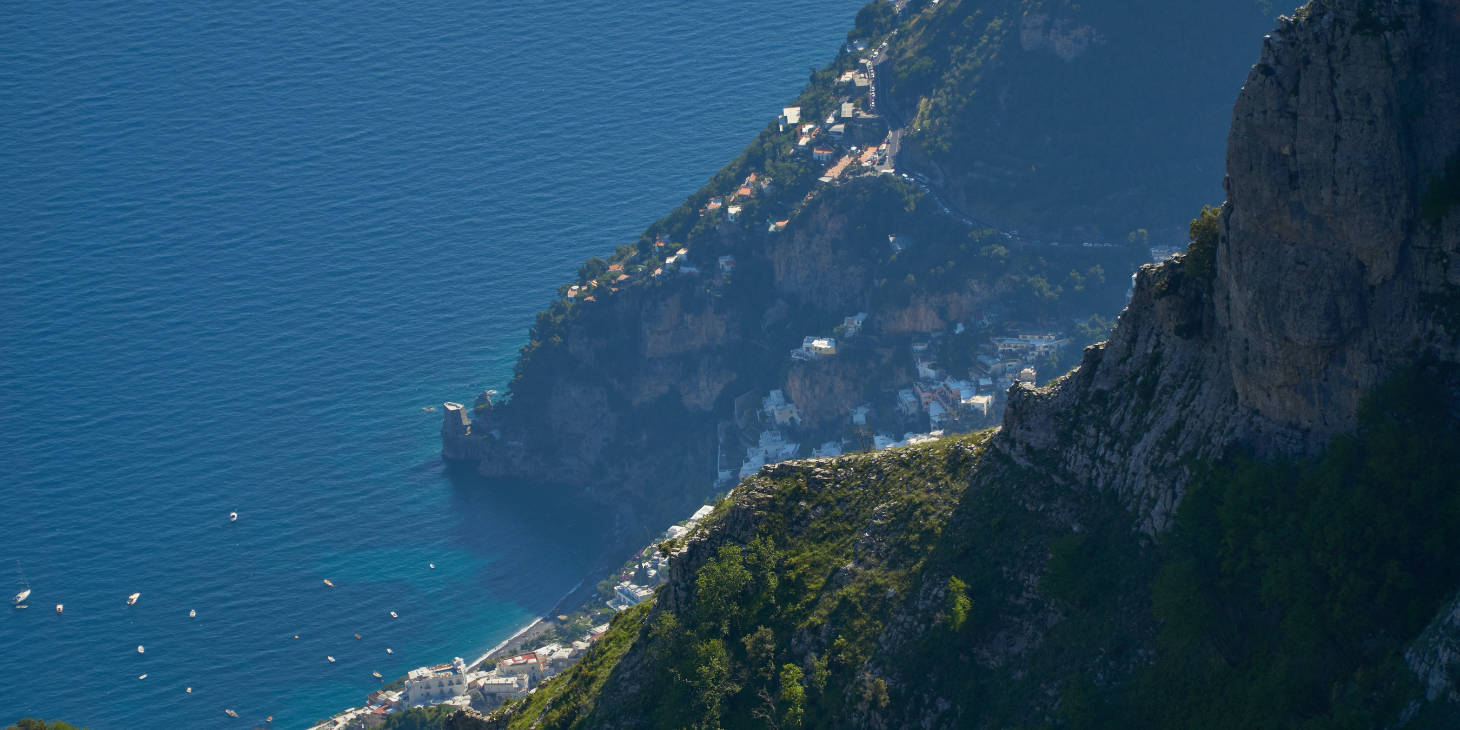Vue sur la Côte Amalfitaine depuis les hauteurs avec falaises escarpées, villages et mer Méditerranée.