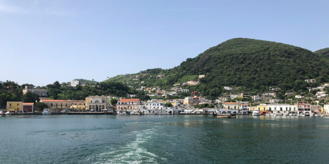 Vue du port d'Ischia et de ses collines verdoyantes depuis un bateau.