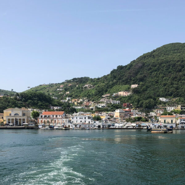 Vue du port d'Ischia et de ses collines verdoyantes depuis un bateau.