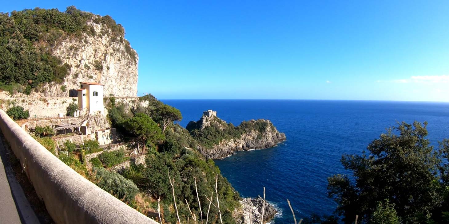 Vue sur Conca dei Marini et la mer de la Côte Amalfitaine, entre falaises, végétation méditerranéenne et eaux bleues.