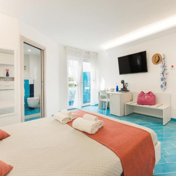Chambre moderne et lumineuse avec un sol en carrelage bleu turquoise typique de Procida.