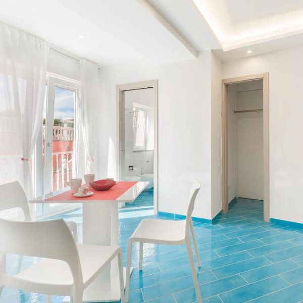 Espace de vie contemporain aux tons blanc et bleu avec un coin repas convivial et baigné de lumière.