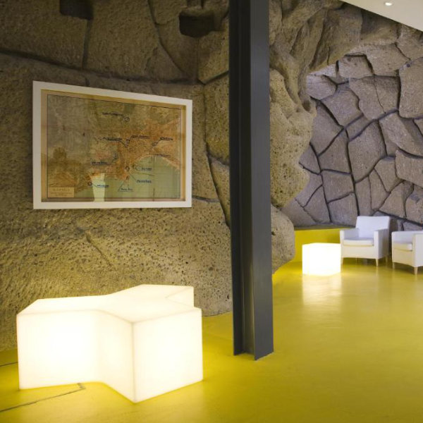 Hall d'entrée design de l'hôtel Correra 241 avec murs en pierre de tuf e mobilier rétroéclairé.