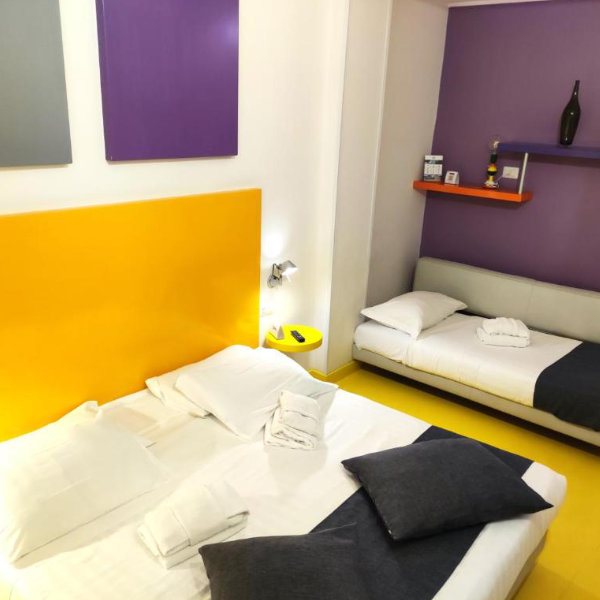 Chambre moderne aux couleurs vives avec un grand lit, un canapé-lit et un design minimaliste.