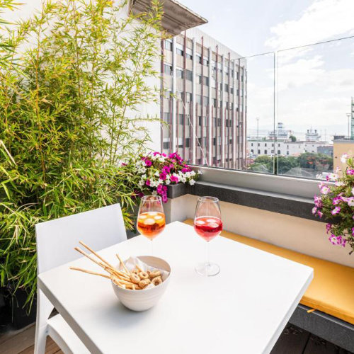 Apéritif sur une terrasse privée à Naples avec deux verres de Spritz et vue sur le port.