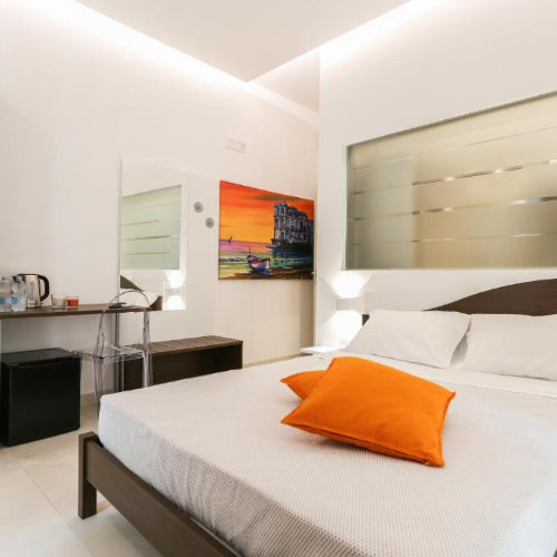 Suite contemporaine avec lit double et coussin orange dans une maison d'hôtes de luxe à Naples.