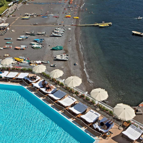 Vue aérienne de la terrasse de la piscine et de la plage de galets de l'hôtel avec des bateaux.