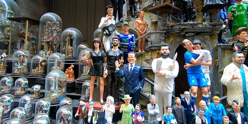 Figurines de crèche napolitaine dans une boutique de San Gregorio Armeno à Naples, représentant personnages célèbres et traditionnels.