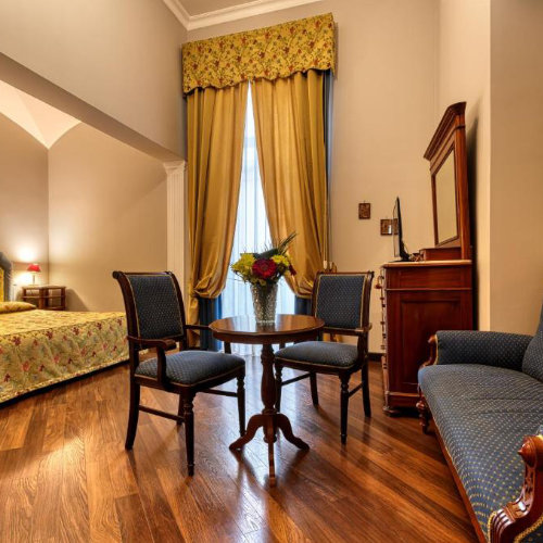 Chambre d’hôtel à Naples avec mobilier classique, parquet et espace confortable pour séjour touristique.
