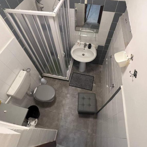 Petite salle de bain moderne et fonctionnelle équipée d'une cabine de douche et d'un carrelage sobre.