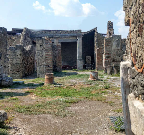 Vue intérieure des ruines de la Domus de Romulus et Rémus à Pompéi avec ses murs antiques et sa cour à ciel ouvert.