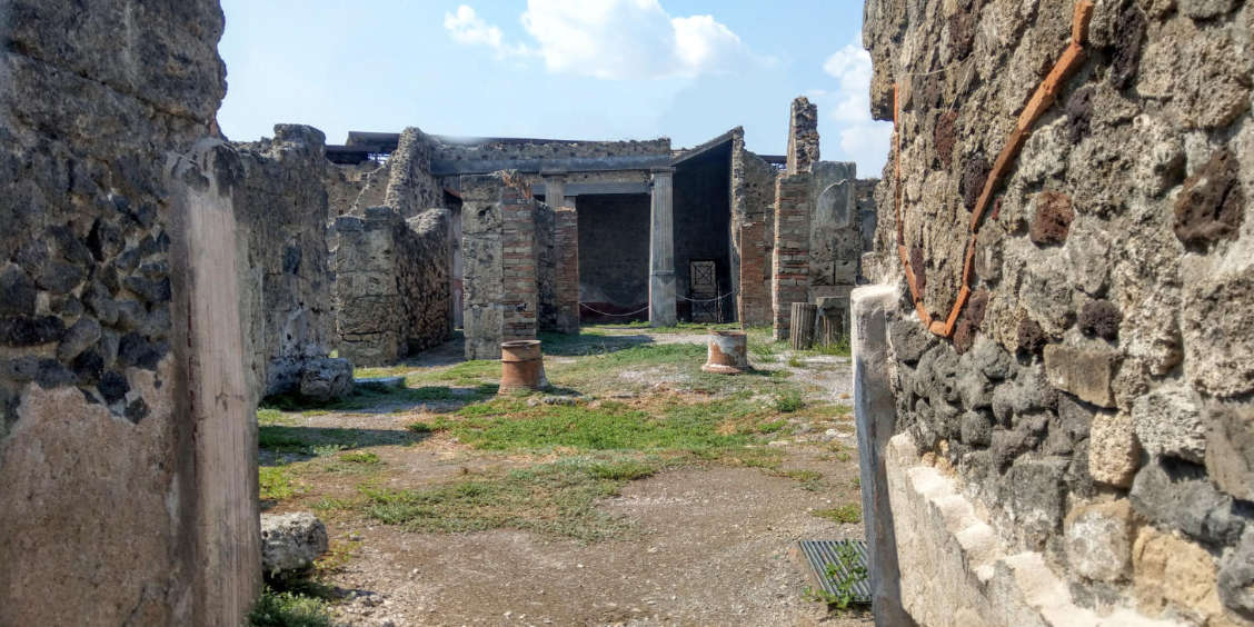 Vue intérieure des ruines de la Domus de Romulus et Rémus à Pompéi avec ses murs antiques et sa cour à ciel ouvert.