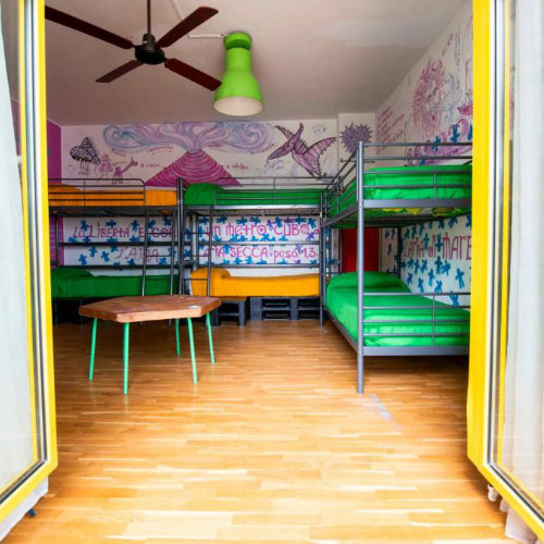 Dortoir de l'Eco Hostel Floreale avec des lits superposés colorés et des murs ornés de fresques et de textes.