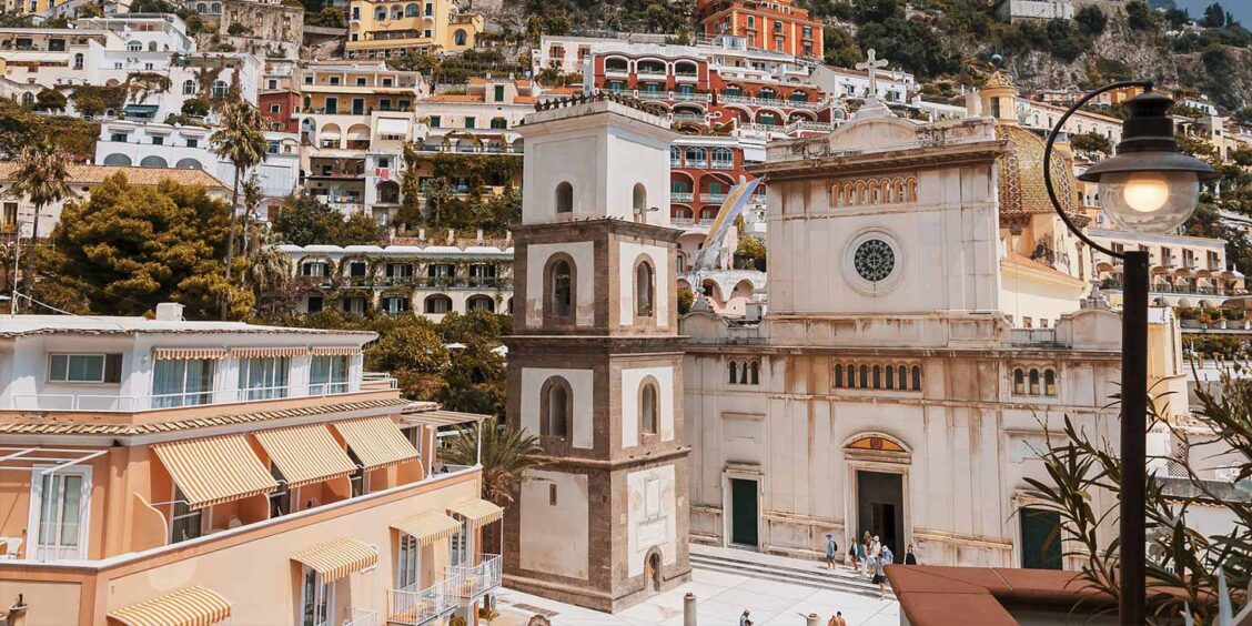 Église Santa Maria Assunta à Positano avec dôme en majolique et maisons colorées de la Côte Amalfitaine.