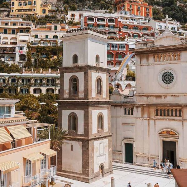 Église Santa Maria Assunta à Positano avec dôme en majolique et maisons colorées de la Côte Amalfitaine.