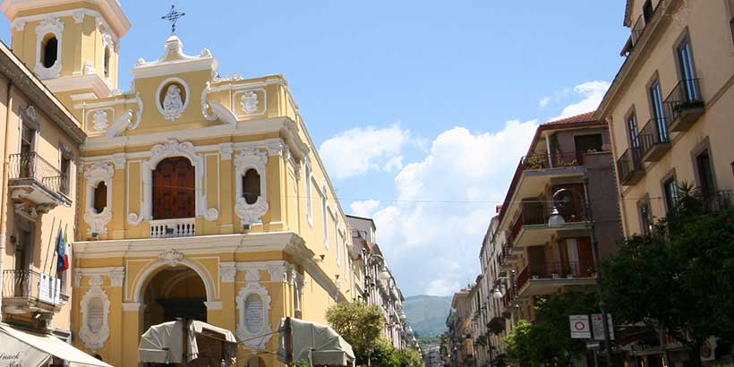 Église Madonna del Carmine à Sorrente avec façade jaune, clocher et rue animée.