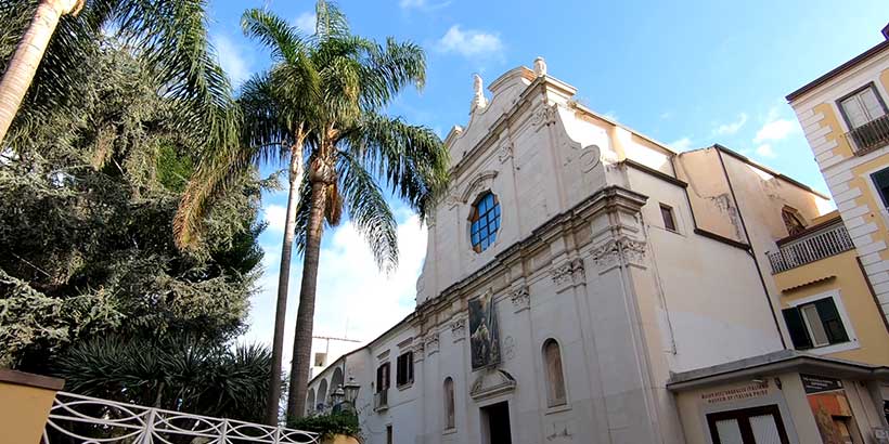 Église San Francesco à Sorrente avec façade baroque, palmiers et jardin.