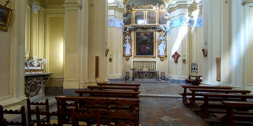 Intérieur de l’église San Paolo à Sorrente avec autel, bancs en bois et décor religieux.