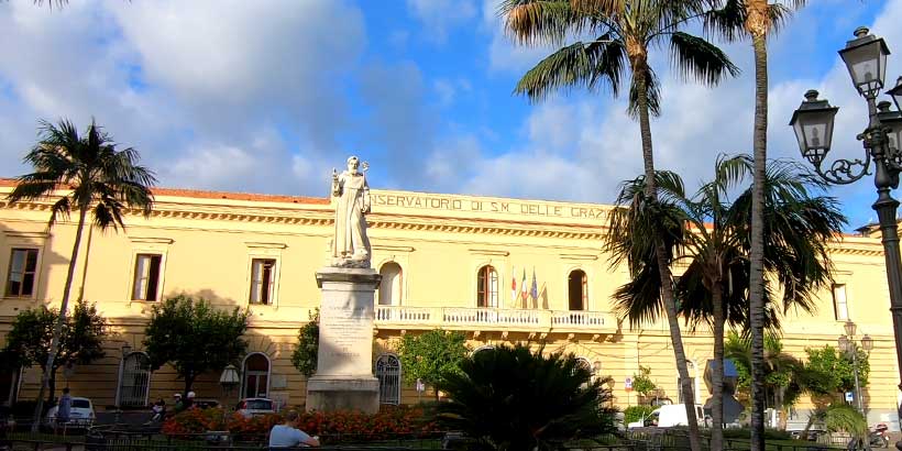 Basilique Sant’Antonino à Sorrente avec statue, palmiers et façade historique.