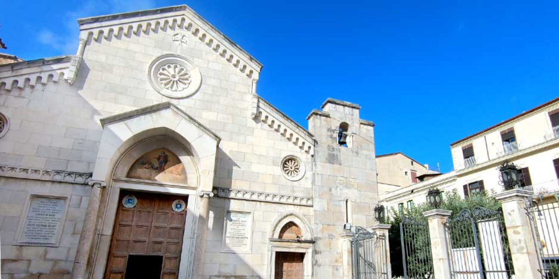 Église historique de Sorrente avec façade claire, rosace et clocher sous un ciel bleu.