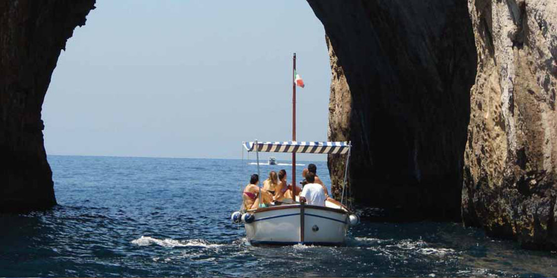 Excursion en bateau depuis Sorrente avec passage sous une arche rocheuse en mer.