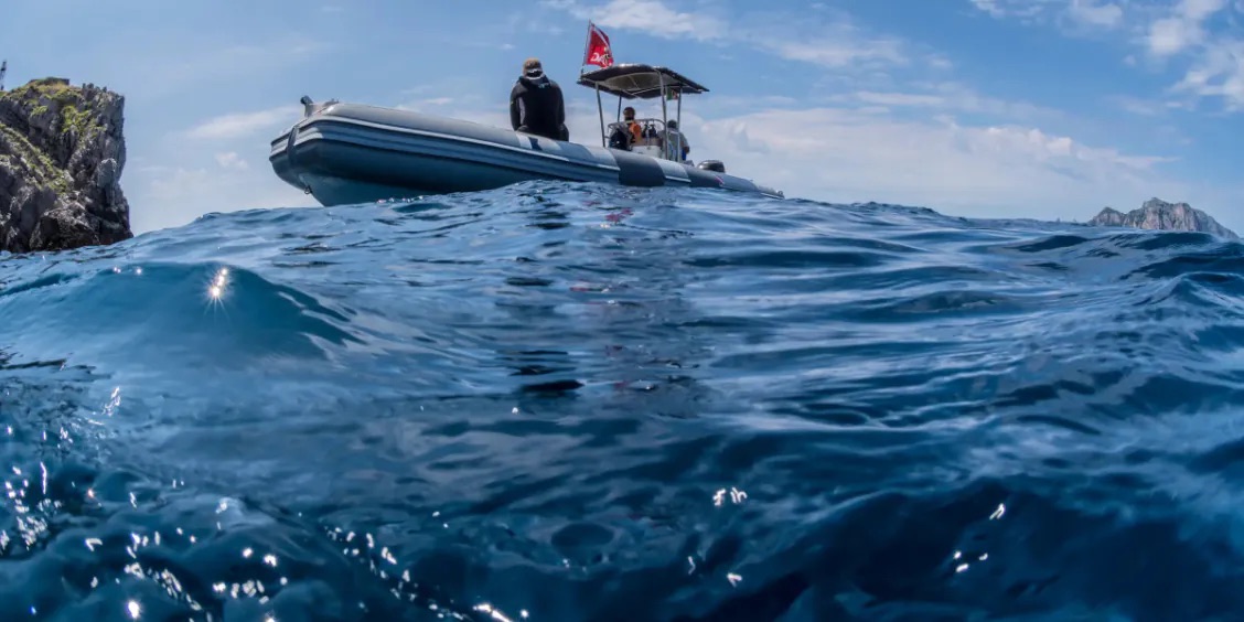 Bateau d’excursion snorkeling au large de Sorrente avec mer bleue et côte rocheuse.