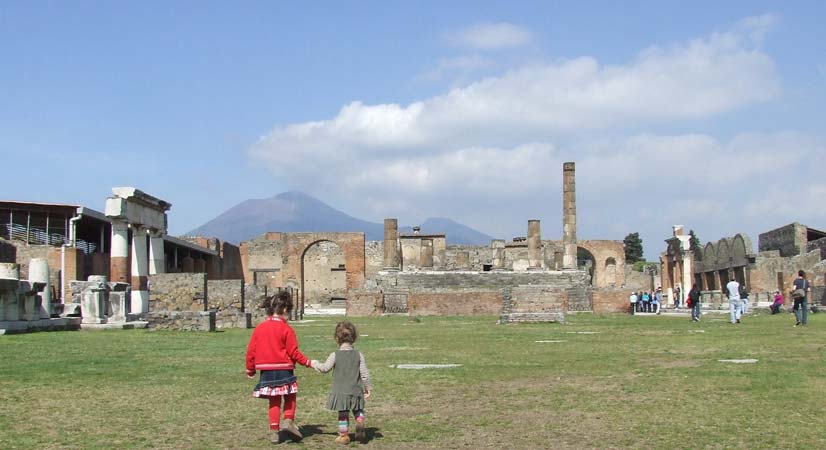 Excursion en famille à Pompéi depuis Sorrente avec enfants, ruines antiques et Vésuve en arrière-plan.