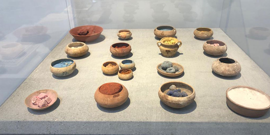 Exposition de pigments colorés en poudre dans des petits bols en céramique au musée.
