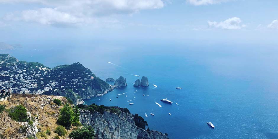 Vue panoramique de la côte de Capri avec les rochers Faraglioni et de nombreux bateaux sur la mer.