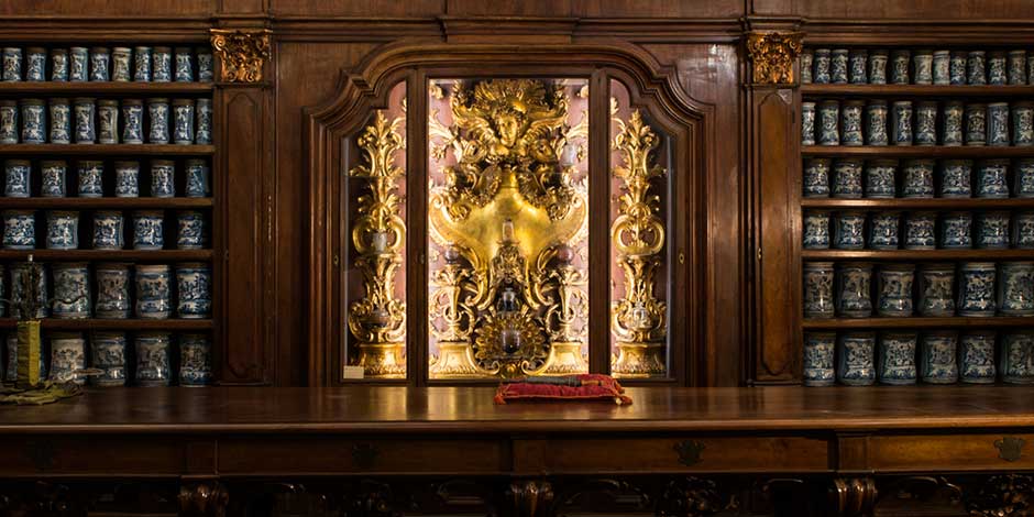 Pharmacie historique des Incurables à Naples avec étagères en bois et pots anciens décorés.