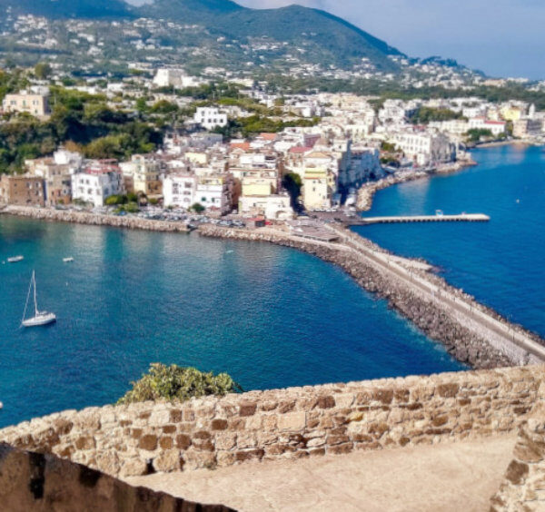 Vue sur Ischia depuis un château avec mer turquoise, village côtier et paysage méditerranéen.