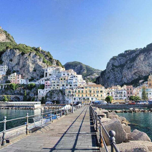 Port d’Amalfi avec embarcadère des ferries, mer et maisons au pied des falaises.