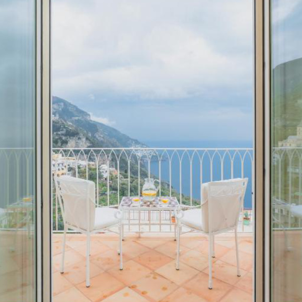 Balcon du Five à Positano avec table, chaises et vue panoramique sur la côte.
