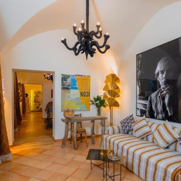 Salon élégant du Five à Positano avec plafond voûté, œuvres d’art et canapé.