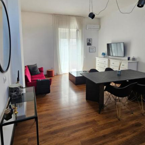 Espace de vie moderne avec parquet, table à manger noire et canapé rouge vif.