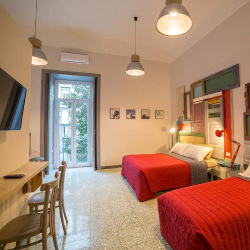 Chambre colorée à Naples avec lits doubles et décoration moderne dans un appartement.