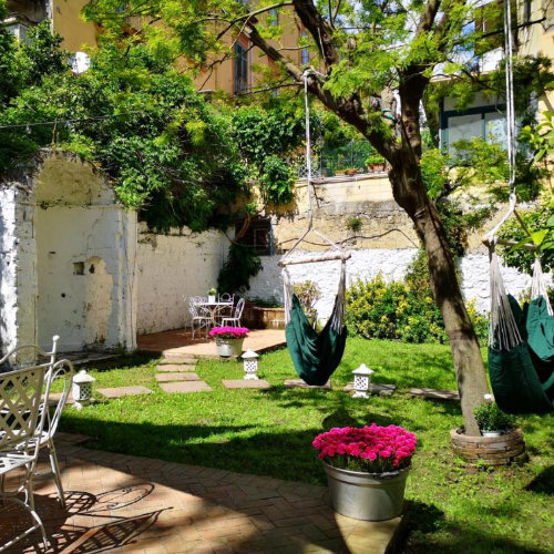 Jardin calme à Naples avec hamacs, arbres et espace détente dans un hébergement.