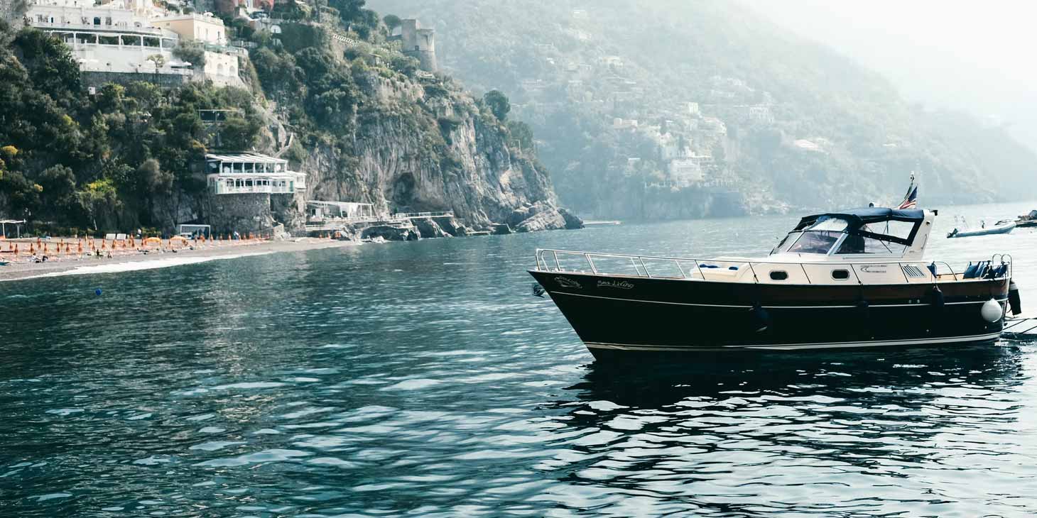 Plage de Fornillo à Positano avec bateau amarré et falaises de la Côte Amalfitaine.
