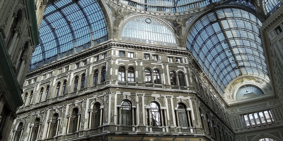 Intérieur de la galerie Umberto I à Naples, avec verrière monumentale, architecture élégante et façades ornées.