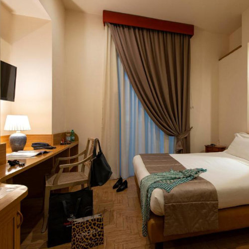 Chambre d'hôtel élégante avec lit double, bureau en bois et tableau classique dans une ambiance chaleureuse.