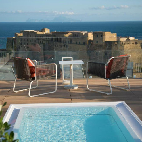 Terrasse avec piscine du Grand Hotel Vesuvio à Naples offrant une vue panoramique sur la mer et le château.