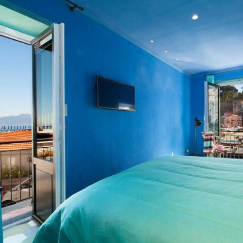 Chambre bleue de Grotta Azzurra à Sorrente avec lit turquoise, balcon et vue sur la mer.