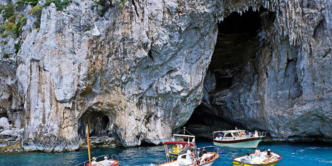 Bateaux de tourisme devant l'entrée rocheuse de la Grotte Blanche à Capri.