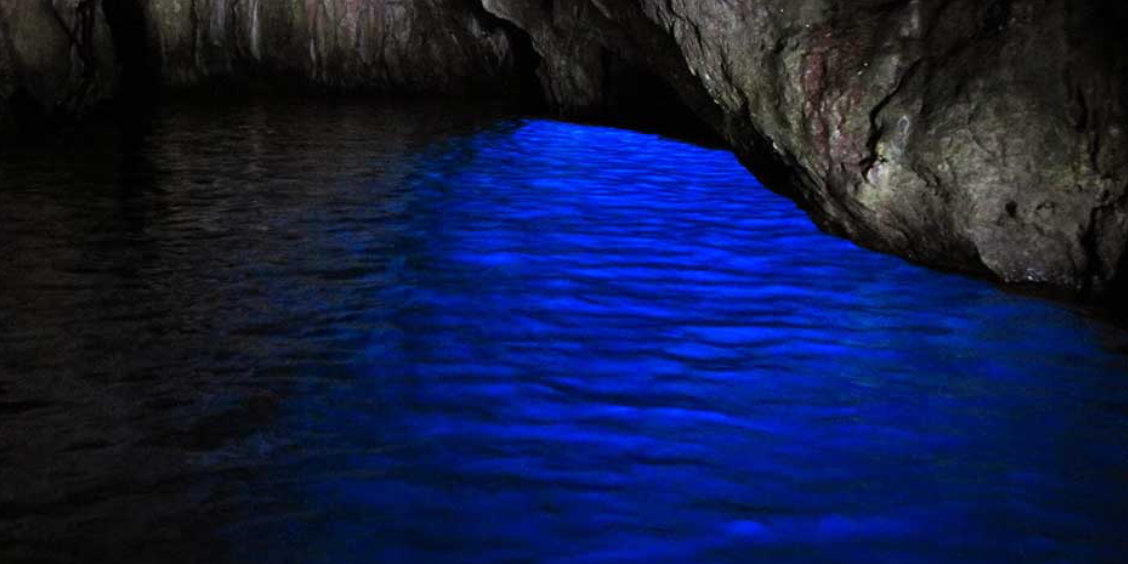Reflets bleu électrique sur l'eau à l'intérieur de la Grotte Bleue de Capri.