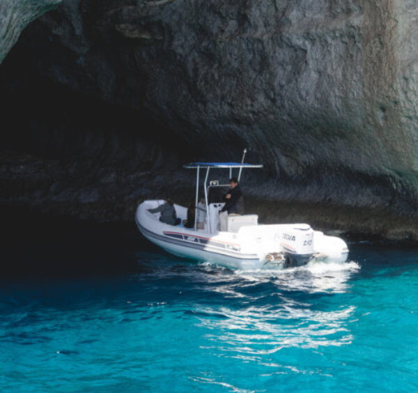 Bateau à l'entrée de la Grotte Verte à Capri avec des eaux émeraude cristallines.