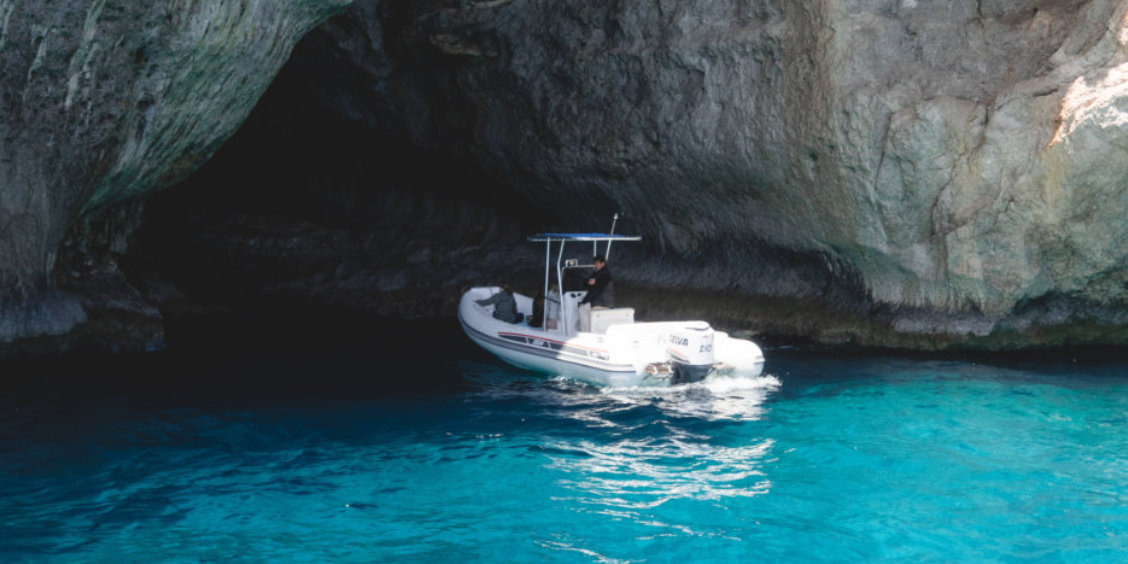 Bateau à l'entrée de la Grotte Verte à Capri avec des eaux émeraude cristallines.