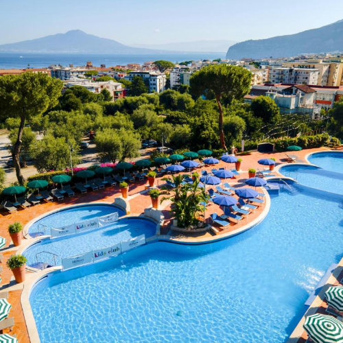 Piscine du Hilton Sorrento Palace à Sorrente avec transats, parasols et vue sur le golfe.